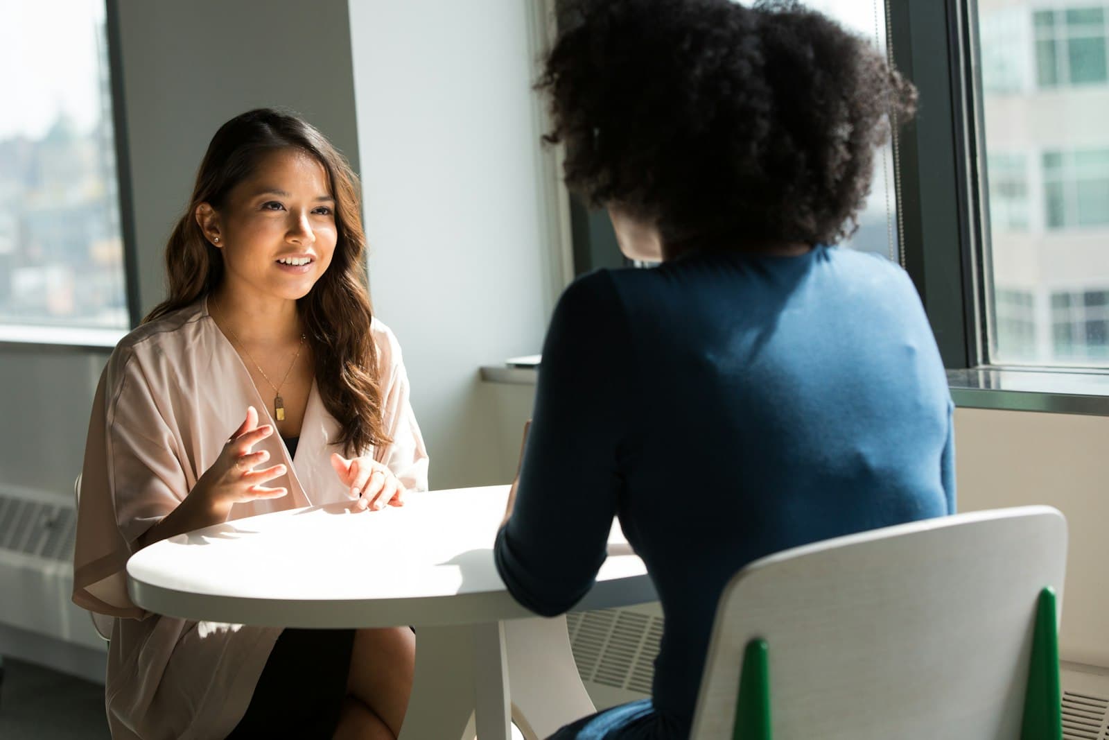 Two women in a warm, sunlit talking-therapy conversation